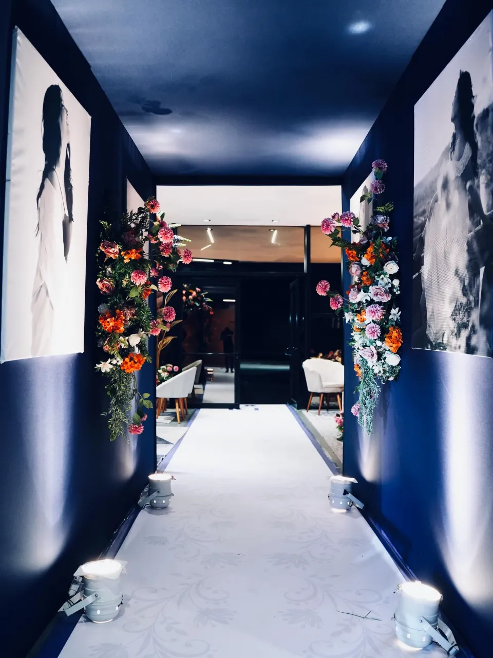 Corredor de entrada de festa de 15 anos com painéis de foto e flores